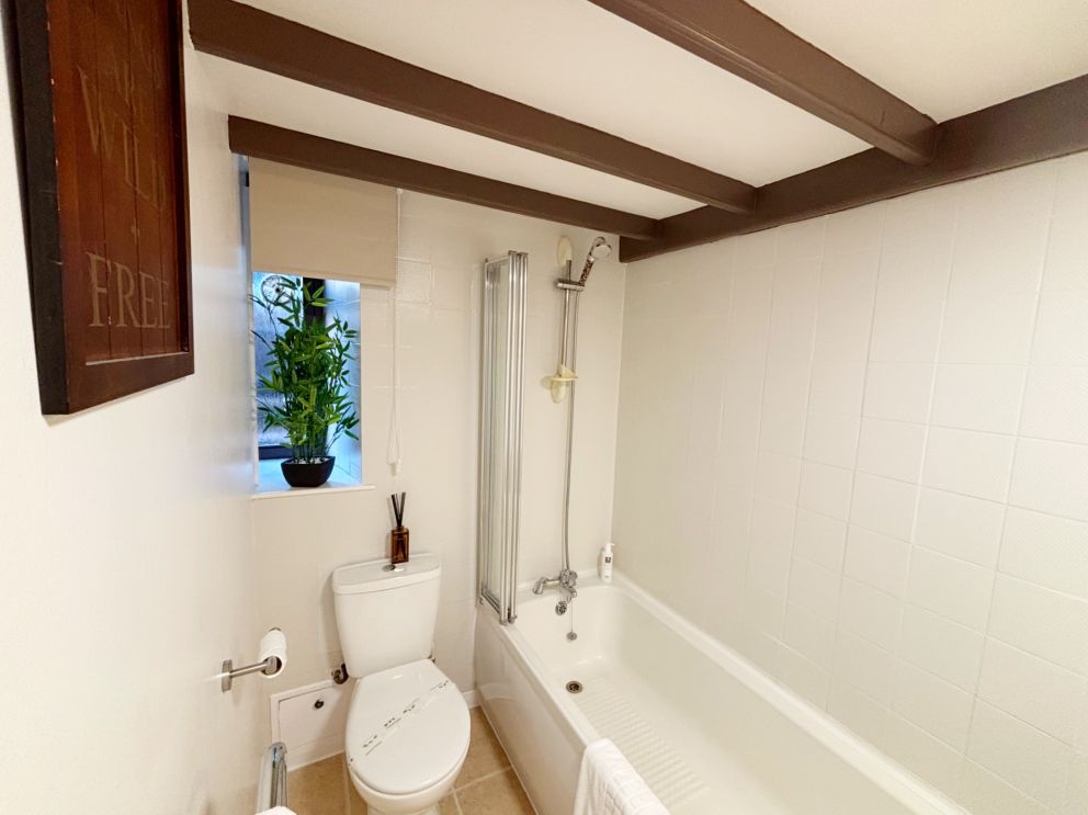 The bathroom at 1 Torwood Gables, Torquay with bath and shower over.